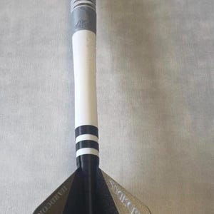 May include: A dart featuring a grey barrel with white ring patterns, a white shaft with two black rings, and a black flight. The flight displays a white snake graphic with red eyes and the text Hardcore and Snakebite printed in silver lettering.