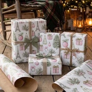 May include: Three gift boxes wrapped in white paper featuring a pattern of pink presents, green pine trees, and the Eiffel Tower. The boxes are tied with natural jute twine and olive green ribbon bows, accompanied by a roll of matching paper.