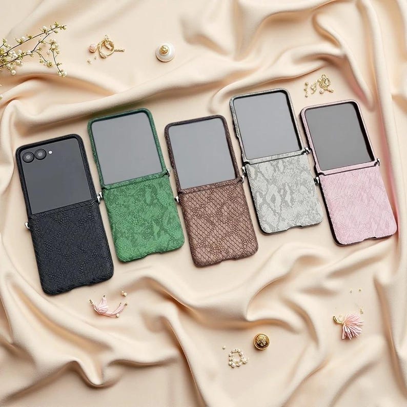 May include: Five rectangular phone cases with a textured snakeskin pattern, arranged in a row. The cases come in black, green, brown, silver, and pink, each featuring a dark screen-like panel on the upper portion and a camera lens cutout.