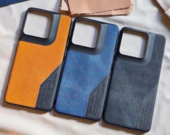 May include: Three rectangular smartphone cases featuring a diagonal colour-blocked design with a textured fabric finish. The cases are orange, blue, and black, each with a black camera cutout and a small label reading Hand Made Ultimate Design.