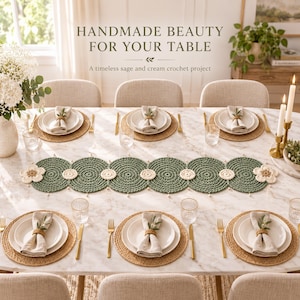 May include: A sage green and cream crochet table runner featuring circular motifs and flower accents, centered on a marble dining table with place settings, white napkins, woven placemats, and text reading HANDMADE BEAUTY FOR YOUR TABLE.