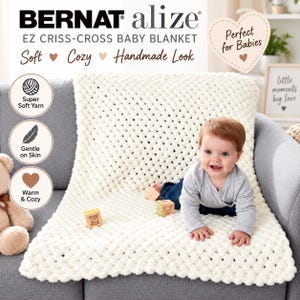 May include: A cream-colored, chunky knit baby blanket with a criss-cross pattern. The blanket is displayed with text reading Bernat Alize EZ Criss-Cross Baby Blanket, Soft, Cozy, Handmade Look, Super Soft Yarn, Gentle on Skin, and Warm & Cozy.