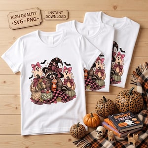 May include: Three white t-shirts featuring a graphic of a raccoon wearing a witch hat and holding a drink, surrounded by pumpkins, ghosts, and plaid fabric. The design includes pink bows and bats. The shirts are displayed with decorative pumpkins.