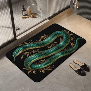 May include: A rectangular floor mat featuring a black background with a large, coiled green snake with iridescent scales. The snake is surrounded by intricate, metallic gold-coloured leaf and vine illustrations that accent the curves of its body.