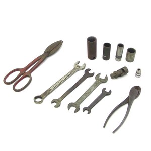 May include: A collection of assorted metal hand tools including a pair of tin snips, four open-ended and combination wrenches, four cylindrical sockets of varying sizes, a universal joint adapter, a small socket bit, and a pair of wire cutters.