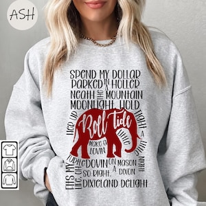 May include: A light gray crewneck sweatshirt featuring a red elephant graphic in the center. The text "Roll Tide" is written in white script across the elephant. Surrounding the graphic is black text with lyrics from the song Dixieland Delight.