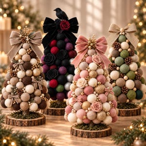 May include: Four decorative tabletop trees constructed from felt balls in various colors, including brown, black, pink, and green. Each tree is topped with a large fabric bow, small pinecones, and gold accents, all mounted on circular wooden bases.
