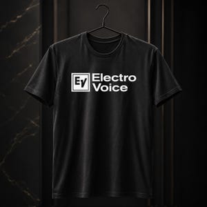 Puede incluir: Una camiseta negra de manga corta con el logotipo blanco de Electro-Voice y las letras EV dentro de un recuadro cuadrado en el pecho. La prenda se muestra en una percha negra, con cuello redondo y un diseño de corte estándar.