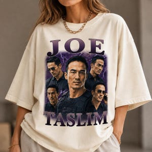 May include: An off-white short-sleeve t-shirt featuring a graphic print of actor Joe Taslim in multiple poses. The design includes the text JOE TASLIM in large purple letters at the top and bottom, set against a purple lightning background.