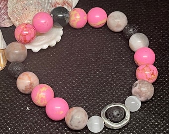 Pink and gray Howlite Beaded 6.5” Diffuser Stackable Bracelet made with pink and gray Howlite, and blach Lava beads. Silver bead charm.