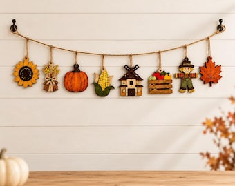 May include: A decorative garland featuring eight wooden ornaments hanging from a jute rope. The ornaments include a yellow sunflower, a wheat sheaf, an orange pumpkin, a corn cob, a brown windmill, a crate of apples, a scarecrow, and a maple leaf.