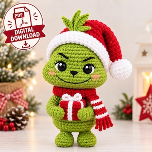 May include: A green crocheted creature with large black eyes, wearing a red and white Santa hat and a matching red and white striped scarf. The figure holds a small red gift box with a white ribbon. A circular badge reads PDF DIGITAL DOWNLOAD.