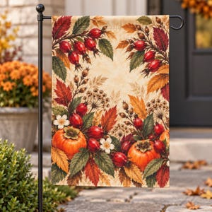 Puede incluir: Una bandera de jardín rectangular con un diseño otoñal estacional que presenta calabazas de color naranja vibrante, escaramujos rojos y hojas de otoño multicolores en tonos amarillos, naranjas y rojos intensos sobre un fondo crema con flores blancas.