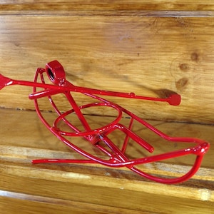 Puede incluir: Una escultura de metal roja de una canoa con un remo. La escultura está hecha de metal delgado y es muy detallada.