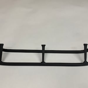 Puede incluir: Perchero de metal negro con tres ganchos. El perchero es curvo en los extremos y tiene un diseño simple y minimalista.