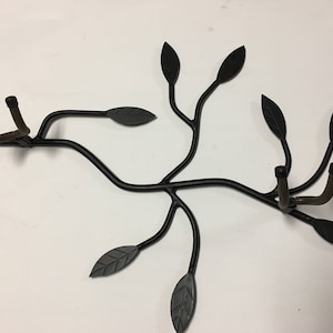 Könnte beinhalten: Schwarzer, wandmontierter Gitarrenhalter aus Metall in Form eines Astes mit Blättern. Der Halter hat zwei Haken zum Aufhängen von Gitarren.