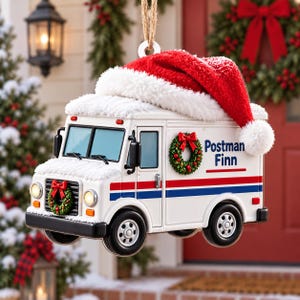 Könnte beinhalten: Ein weißes Postauto-Ornament mit einem roten und blauen Streifen, einem kleinen grünen Kranz am Frontgrill und einem weiteren an der Seite mit dem Text Postman Finn. Das Fahrzeug ist mit einer roten und weißen Plüsch-Weihnachtsmannmütze versehen.