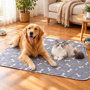 May include: A rectangular pet mat in a medium gray color featuring a repeating white bone pattern. The mat has a quilted texture and is positioned flat on a wooden floor, providing a surface for a golden retriever dog and a fluffy cat to rest.
