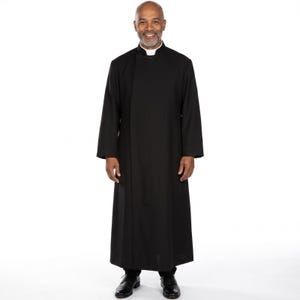 May include: A black cassock featuring a high mandarin collar with a white clerical tab insert. This long-sleeved, floor-length garment has a clean, solid black finish with a concealed front closure, providing a structured and formal appearance.