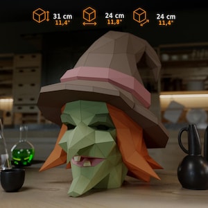 Könnte beinhalten: Eine Low-Poly-Papierkunst-Skulptur eines Hexenkopfes mit grünem Gesicht, orangefarbenem Haar und einem braunen Hut mit rosa Band. Die Skulptur misst 31 cm in der Höhe, 24 cm in der Breite und 24 cm in der Tiefe, wie in der Abbildung angegeben.