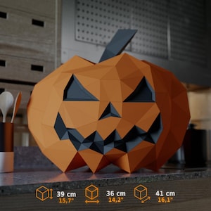 May include: A low-poly geometric pumpkin sculpture in orange with dark gray triangular eyes, nose, and a jagged mouth. The dimensions are 39 cm (15.7 inches) in height, 36 cm (14.2 inches) in width, and 41 cm (16.1 inches) in depth.