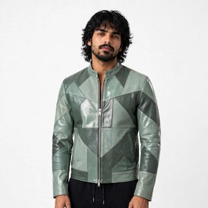 Può includere: Una giacca a maniche lunghe caratterizzata da un design patchwork composto da vari pannelli in pelle in diverse tonalità di verde salvia e verde oliva. La giacca presenta un colletto alla coreana, una zip centrale in metallo argentato e maniche lunghe.