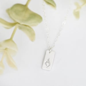 May include: A silver necklace with a rectangular pendant featuring a stylised heart symbol.