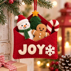 Könnte beinhalten: Ein roter Filz-Weihnachtsschmuck in Umschlagform mit dem weißen Schriftzug JOY und einer weißen Schneeflocke. Im Umschlag befinden sich ein Schneemann aus Filz mit grünem Schal, ein grüner Weihnachtsbaum mit gelbem Stern, ein Lebkuchenmann und eine Zuckerstange.