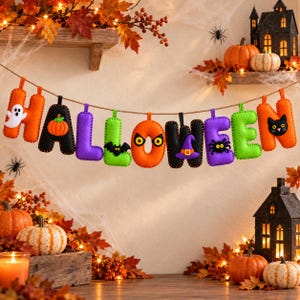 May include: A felt Halloween banner featuring individual letters in orange, black, purple, and green. Each letter displays festive motifs including a ghost, pumpkin, bat, eyes, witch hat, spider, and black cat, all strung together on a rustic twine.