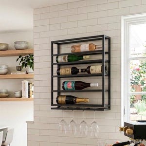 May include: A rectangular black metal wall-mounted wine rack featuring five horizontal shelves for bottle storage and a bottom rack for hanging four stemware glasses. The rack holds five assorted wine bottles of varying colors and labels.