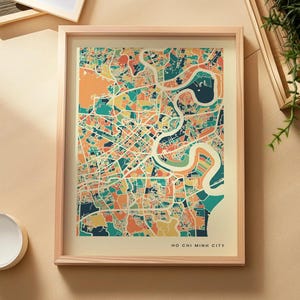 Könnte beinhalten: Ein gerahmter Kartendruck von Ho Chi Minh Stadt mit einem farbenfrohen, abstrakten Straßennetz in Blaugrün, Orange, Gelb und Dunkelblau. Die Karte ist auf einem cremefarbenen Hintergrund platziert, mit dem Text Ho Chi Minh City unten rechts.