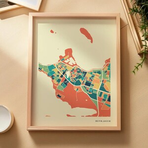 Könnte beinhalten: Ein gerahmter Stadtplan von Reykjavik mit einem stilisierten Straßennetz in Koralle, Petrol, Gelb und Creme. Die Karte zeigt geometrische Häuserblöcke und Küstenlinien auf hellem Hintergrund mit dem Schriftzug REYKJAVIK in der Ecke.