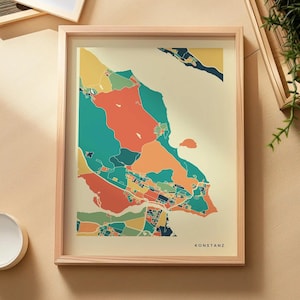 Könnte beinhalten: Ein gerahmter Kunstdruck einer Karte von Konstanz mit einem stilisierten, farbenfrohen Grafikdesign aus türkisfarbenen, orangefarbenen, gelben und dunkelblauen Flächen auf cremefarbenem Grund. Das Wort KONSTANZ steht in schwarzen Großbuchstaben unten rechts.
