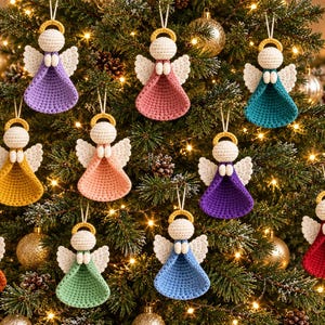 Op de afbeelding: Een verzameling van tien gehaakte engelenornamenten die in een kerstboom hangen. Elke engel heeft een crèmekleurig hoofd, witte vleugels, een gouden halo en een jurk in een unieke effen kleur, waaronder paars, roze, taling, geel, perzik, violet, oranje, groen, blauw en rood.