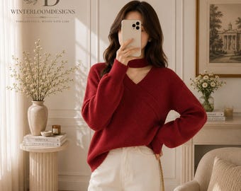 Puede incluir: Un suéter de manga larga en color rojo intenso con textura de punto acanalado, escote en V con detalle de cuello alto y un diseño cruzado en la parte delantera. El suéter se combina con pantalones color blanco hueso y tiene un corte holgado.
