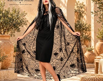Puede incluir: Un vestido negro sin mangas hasta la rodilla combinado con una capa negra transparente con capucha que presenta un intrincado patrón de telarañas y arañas. El logotipo de Winterloom Designs es visible en la esquina superior izquierda.