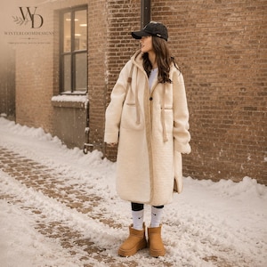 May include: A long, cream-colored, textured fleece coat with a hood, long sleeves, and two front pockets. The coat features a single button closure and tan trim along the edges. It is worn with a black baseball cap, white socks, and tan boots.