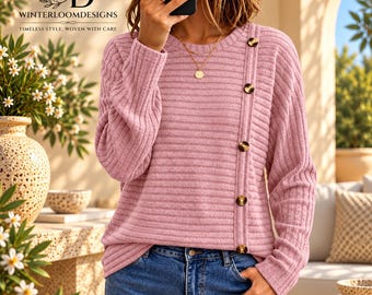 Puede incluir: Un suéter de punto acanalado de manga larga en un suave color rosa malva. El suéter presenta un cuello redondo y una fila vertical de cinco botones de color marrón oscuro moteado que bajan por el lado izquierdo del panel frontal.
