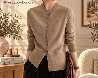 Puede incluir: Un cárdigan beige de manga larga con cuello redondo y una hilera vertical de pequeños botones en el centro. La prenda tiene puños y dobladillo acanalados. El texto WinterloomDesigns es visible en la esquina superior izquierda.