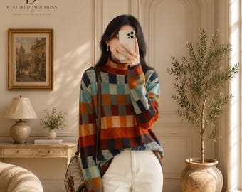 Puede incluir: Un suéter de cuello alto y manga larga con un patrón de cuadros multicolor en tonos naranja, azul y marrón, combinado con pantalones vaqueros blancos y un bolso de hombro de cuero marrón con cierre dorado.