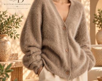 Puede incluir: Un cárdigan beige con cuello en V, acabado de punto difuso y texturizado, mangas largas con puños fruncidos y tres botones visibles en la parte delantera. La prenda se lleva sobre pantalones claros. El logotipo WinterloomDesigns es visible.