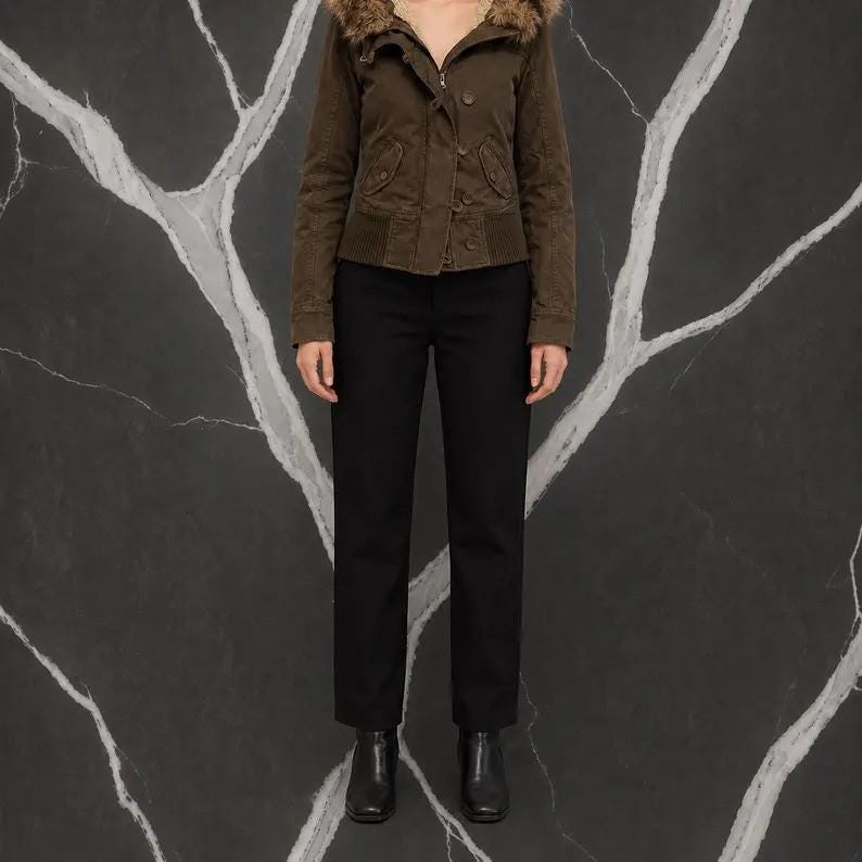 May include: A dark brown bomber jacket with a faux fur-trimmed hood, a front zipper closure, and ribbed cuffs, paired with solid black trousers and black ankle boots. The jacket features two front pockets with button flaps and a structured waistband.