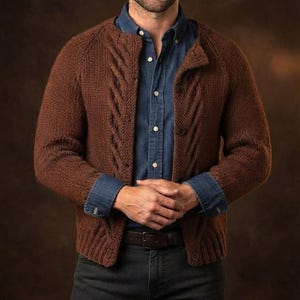Peut inclure: Un gilet en tricot marron avec un motif torsadé le long de l'ouverture avant, porté sur une chemise bleue à boutons et un jean gris foncé. Le gilet a des manches longues et un ourlet côtelé, superposé à une chemise et une ceinture marron.