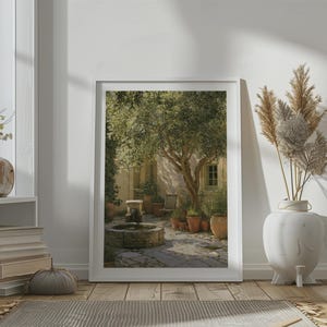 Könnte beinhalten: Ein gerahmter Wandkunstdruck, der einen sonnendurchfluteten mediterranen Innenhof mit einem Steinbrunnen, einem großen Baum und verschiedenen Topfpflanzen zeigt. Die Szene bietet warmes goldenes Licht, Steinpflaster und ein rustikales Gebäude.