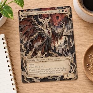 Puede incluir: Una carta coleccionable rectangular titulada Valgavoth, Harrower of Souls, con una ilustración oscura y superpuesta de un demonio con cuernos y alas andrajosas. El texto incluye Legendary Creature, Elder Demon, Flying, Ward y 4/4.