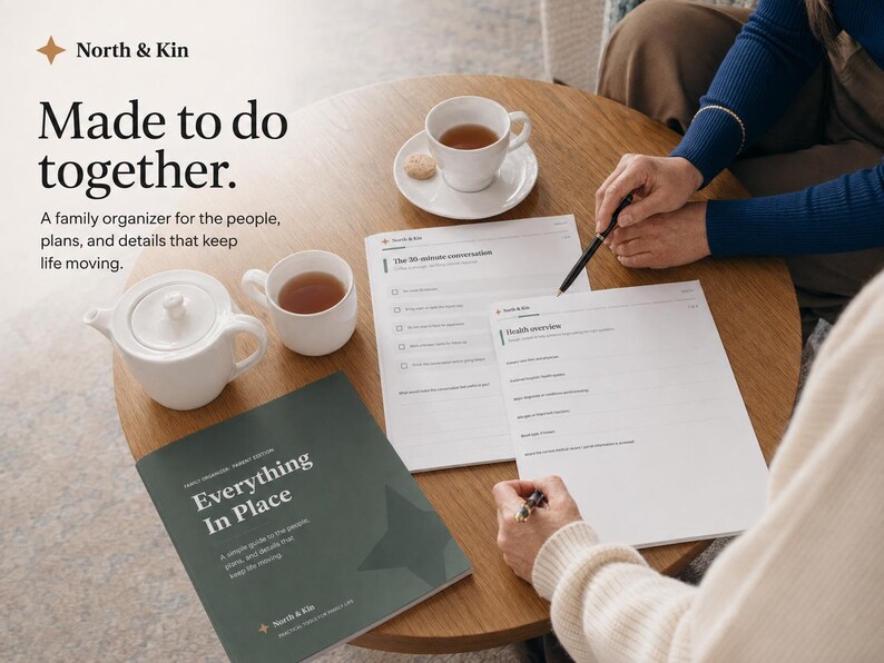 Printed Everything in Place pages and cover on a table as two family members complete the organizer together with pens and tea.
