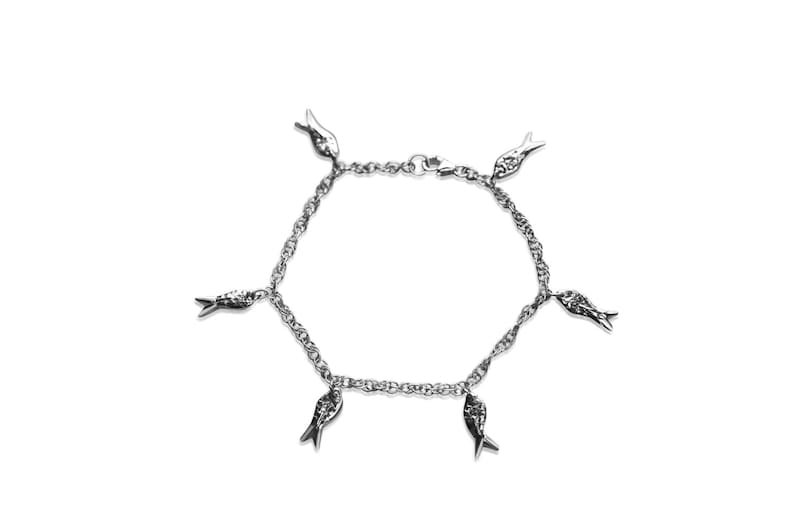 May include: A silver bracelet with a chain link design and five small fish charms hanging from it.