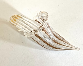 May include: A clear glass vase with gold and white stripes. The vase is shaped like a shoe and has a ruffled top.