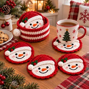 Puede incluir: Un juego de posavasos redondos de ganchillo con forma de muñeco de nieve, con gorros de Papá Noel rojos, pompones blancos y detalles de acebo verde. Los posavasos se guardan en una cesta de ganchillo a rayas rojas y blancas.