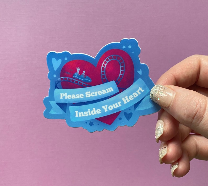 May include: A blue and red heart-shaped sticker with a roller coaster inside. The sticker has the text "Please Scream Inside Your Heart" on it.